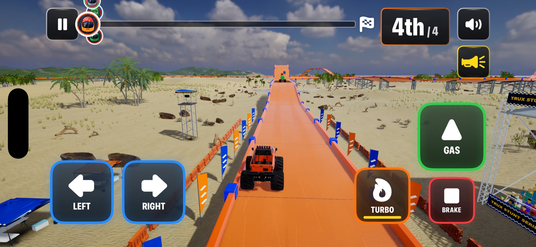 Monster trucks race along a giant orange track on the beach.